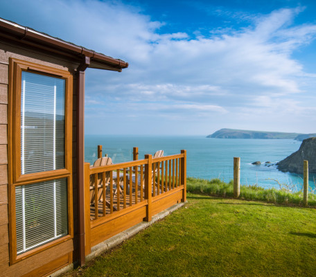 Side view of a lodge at Fishguard Bay Resort with decking that overlooks the sea