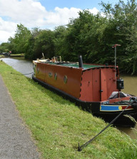 Red narrow boat moored on a canal next to a towpath