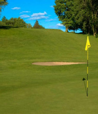 Green golf course, flag and bunker