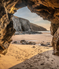 Sandy beach viewed from the entrance to a cave at Holywell beach in Cornwall