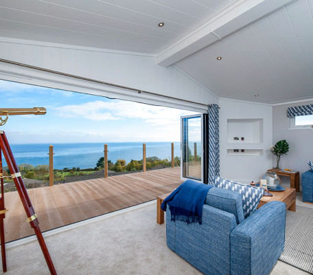 Lounge with blue comfy chairs and views of the sea through large bifold doors