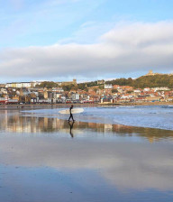 Man walking on beach about to surf in north east england
