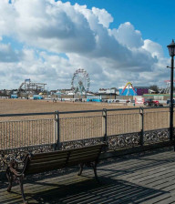 Skegness beach front with benches and the pier and ferris wheel in the distance