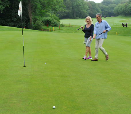 Man and woman chatting while walking towards the flag on a golf course