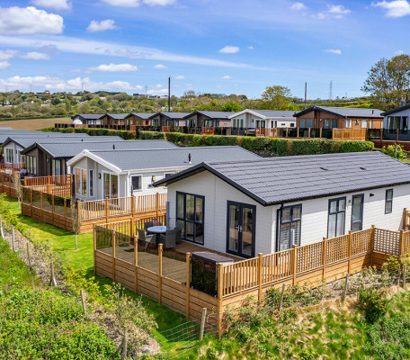 Exterior shot of white and grey lodges at Juliots Well Holiday Park, Cornwall