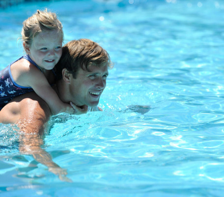 Father with daughter on his back in swimming pool at Seaview Gorran Haven in Cornwall