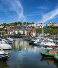 Boats in harbour in front of colourful houses on a hill in Somerset