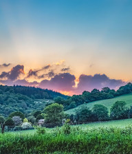 Beautiful sunset over The Wye Valley, purple clouds, green grass, hills of trees