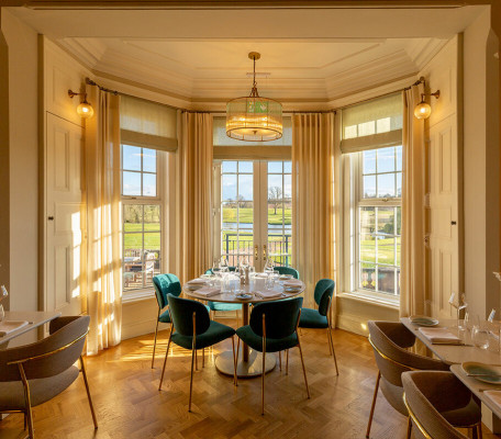 Bay window seating with modern velvet chairs and dining tables in the main Manor House