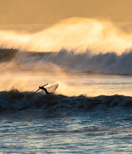 Woolacombe beach, Man surfing on wave at sunset